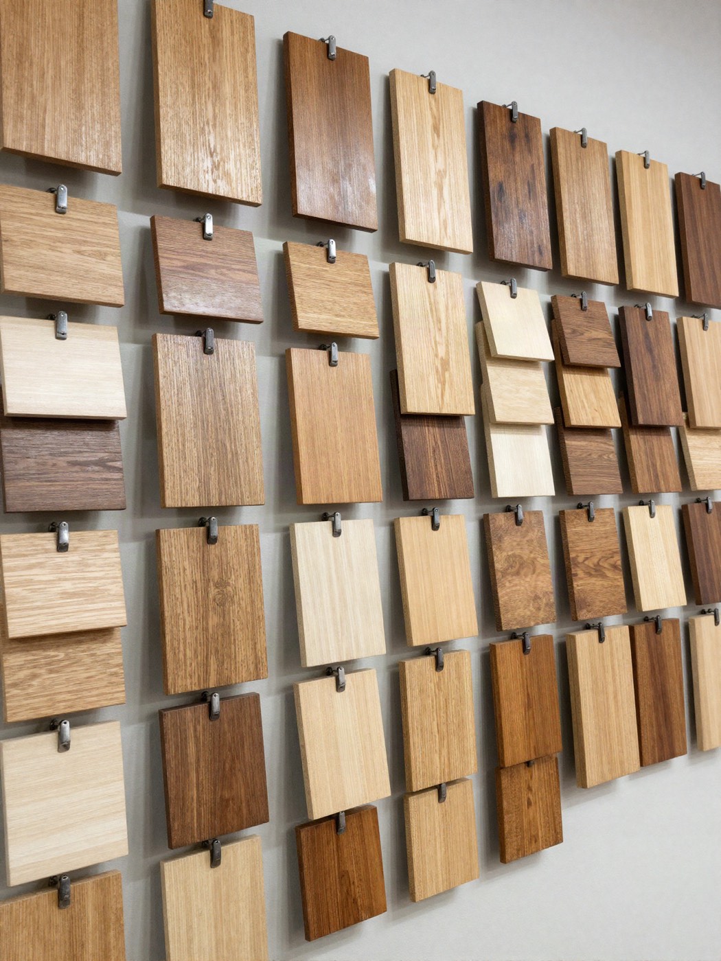 Musterwand mit vielen kleinen Holzbrettchen in hellen bis dunklen Tönen und verschiedenen Oberflächen